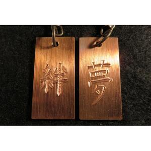 刀匠が銅板のキーホルダーに文字をお入れします。