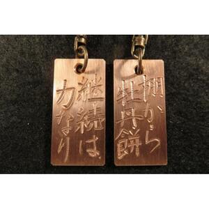 刀匠が銅板のキーホルダーに文字をお入れします。