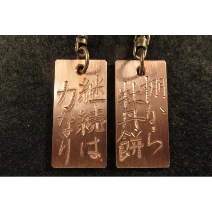 刀匠が銅板のキーホルダーに文字をお入れします。